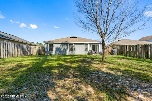 rear view of property featuring a yard and a fenced backyard