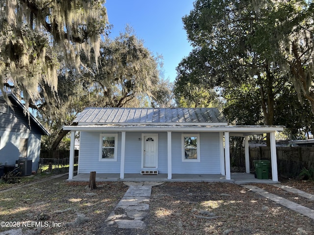 view of front of home featuring metal roof, covered porch, and fence