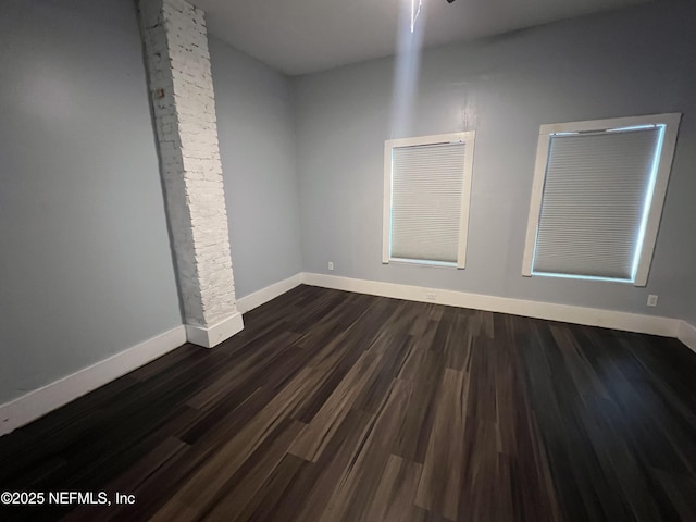 empty room featuring dark wood-type flooring and baseboards