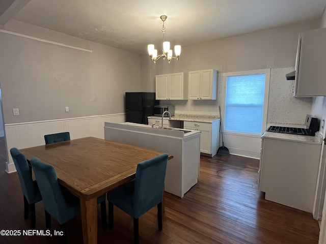 dining space featuring a notable chandelier, dark wood-style flooring, and wainscoting