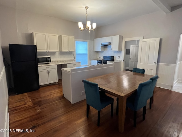 dining room with a chandelier, a wainscoted wall, beamed ceiling, and dark wood finished floors