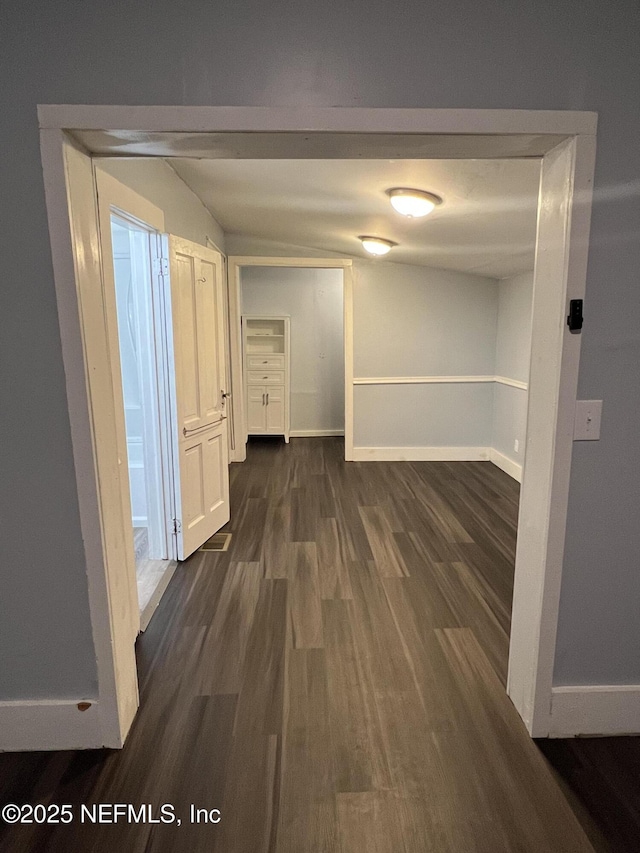 corridor featuring dark wood finished floors and baseboards