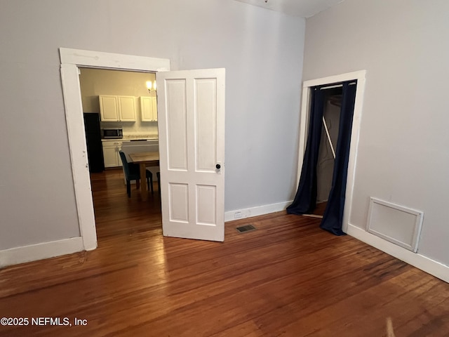 unfurnished room with wood finished floors, visible vents, and baseboards