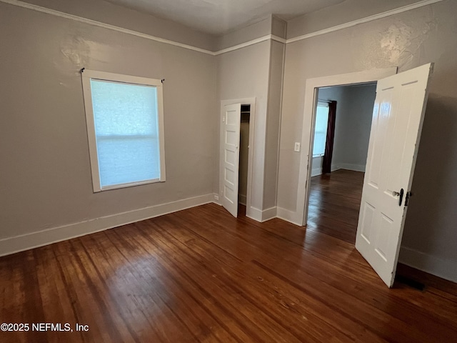 unfurnished bedroom with baseboards and dark wood-style flooring