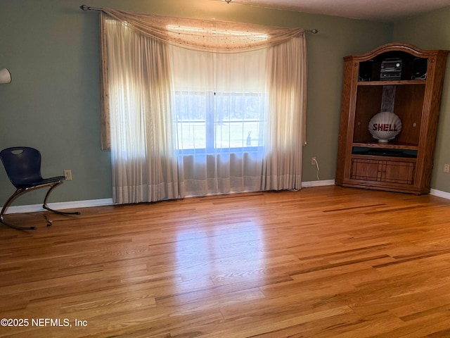 spare room with baseboards and wood finished floors