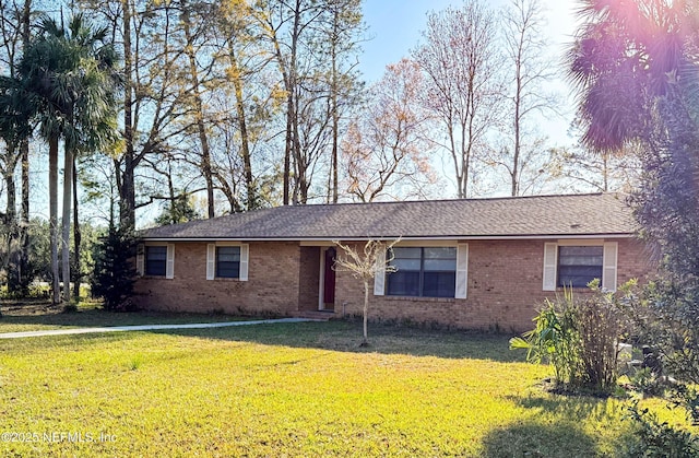 ranch-style home with brick siding, a front lawn, and roof with shingles