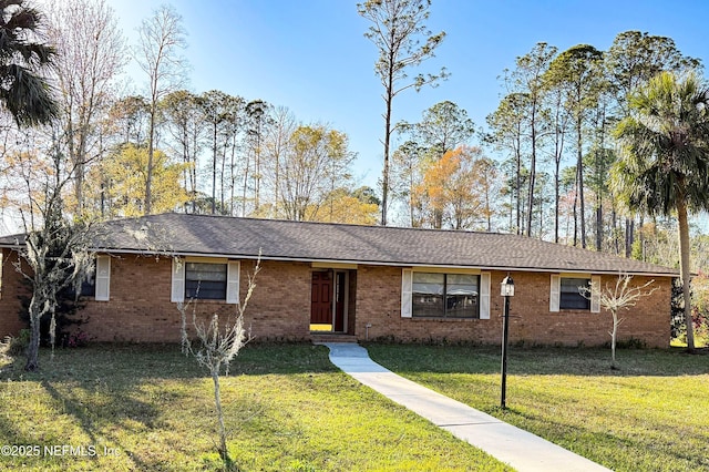 ranch-style house featuring brick siding, a front lawn, and roof with shingles