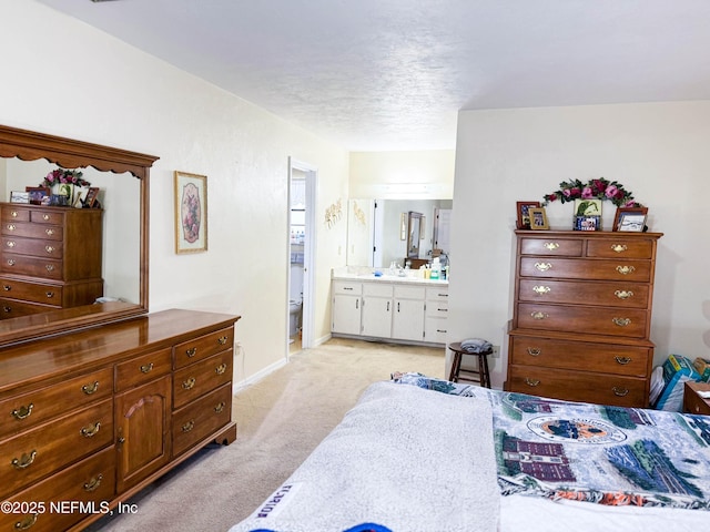 bedroom with baseboards, ensuite bathroom, and light carpet