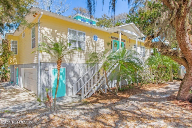 view of home's exterior featuring a porch, stairway, a garage, and driveway