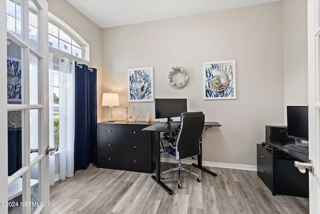 office space with light wood-style flooring, french doors, and baseboards