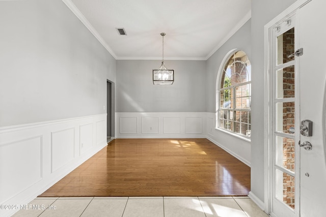 109 N Lake Cunningham Ave, Saint Johns, FL 32259 - unfurnished dining area with a wainscoted wall, visible vents, crown molding, tile patterned floors, and a notable chandelier