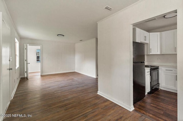 kitchen featuring visible vents, dark wood finished floors, freestanding refrigerator, black range with gas stovetop, and white cabinetry