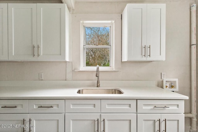 kitchen with white cabinetry, light countertops, and a sink