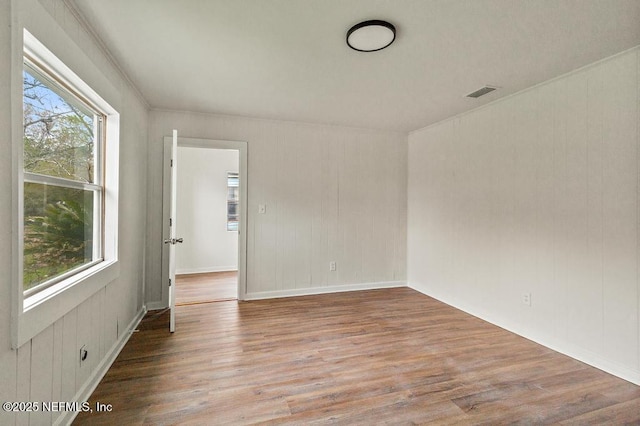 unfurnished room featuring visible vents, plenty of natural light, and wood finished floors