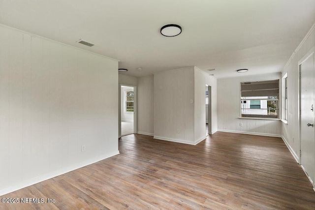 empty room featuring wood finished floors, visible vents, and baseboards