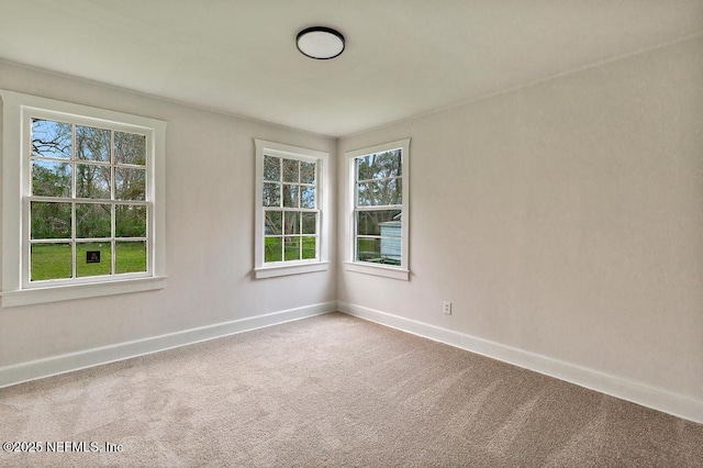 carpeted spare room featuring baseboards and plenty of natural light