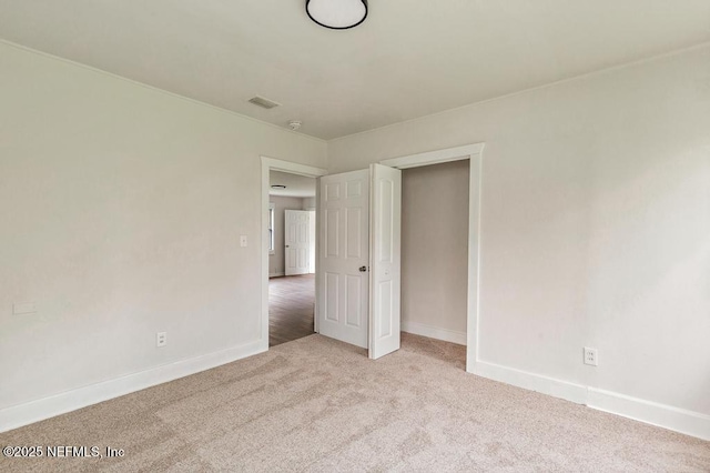 empty room featuring carpet flooring, visible vents, and baseboards