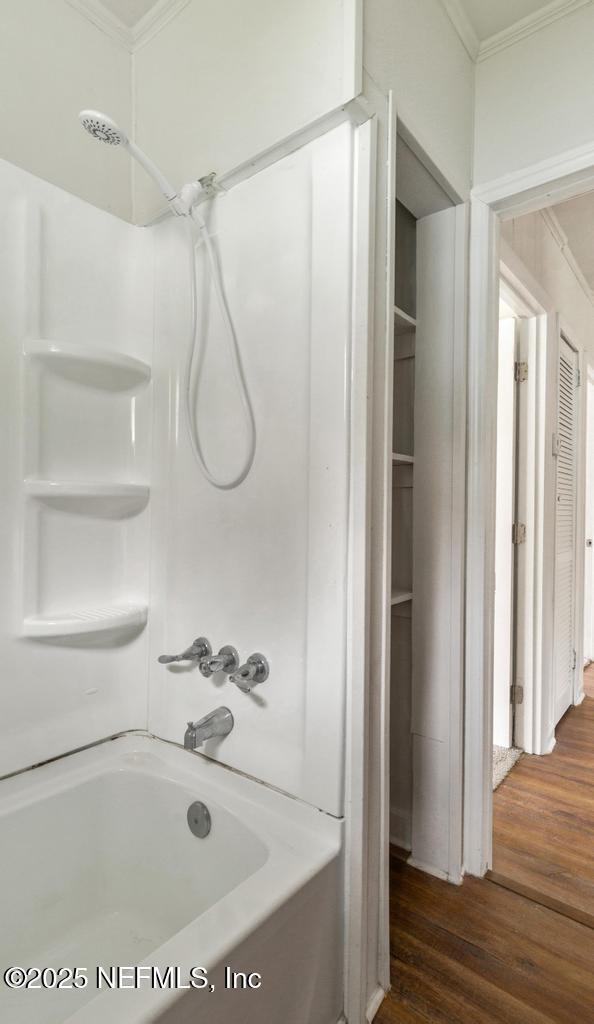 full bath featuring wood finished floors, shower / bathing tub combination, and ornamental molding