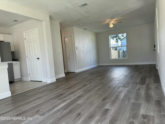 unfurnished living room with wood finished floors, visible vents, and baseboards