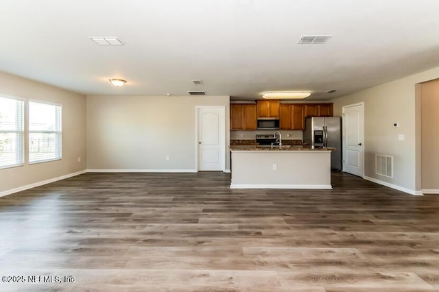 kitchen featuring brown cabinetry, visible vents, appliances with stainless steel finishes, and open floor plan