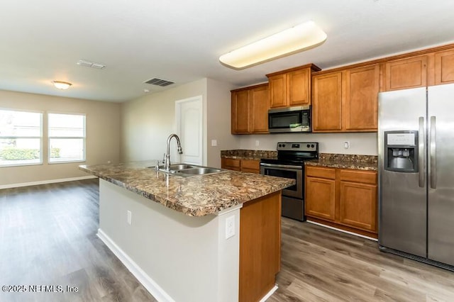 kitchen with brown cabinets, visible vents, appliances with stainless steel finishes, and a sink