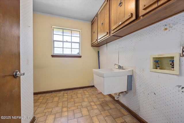 clothes washing area featuring baseboards, ornamental molding, washer hookup, brick floor, and cabinet space