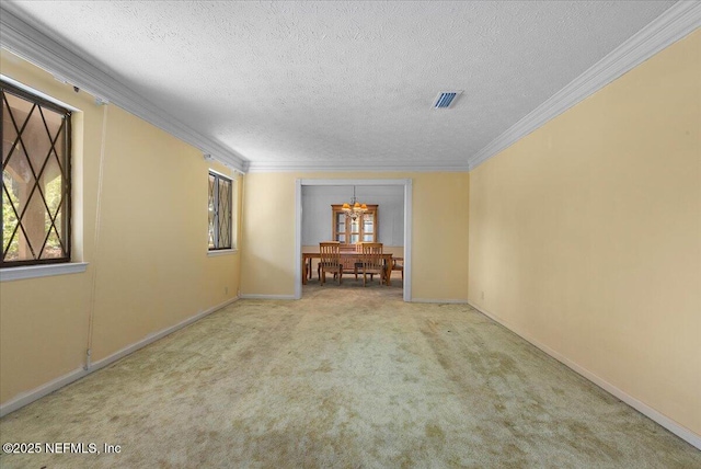 spare room featuring carpet, baseboards, visible vents, a textured ceiling, and crown molding