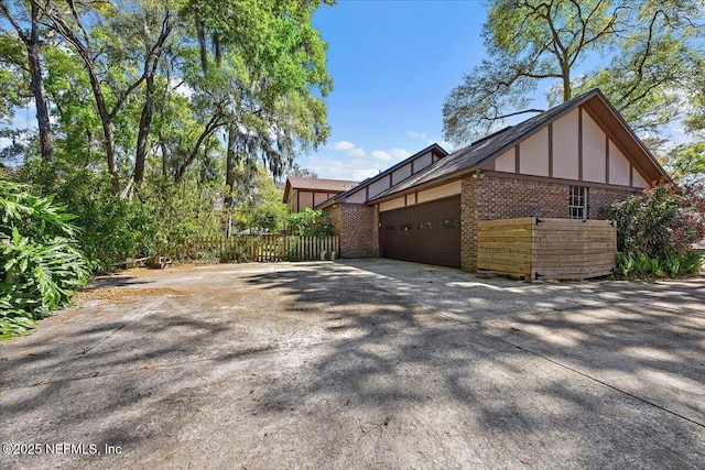 view of home's exterior featuring fence, driveway, stucco siding, a garage, and brick siding