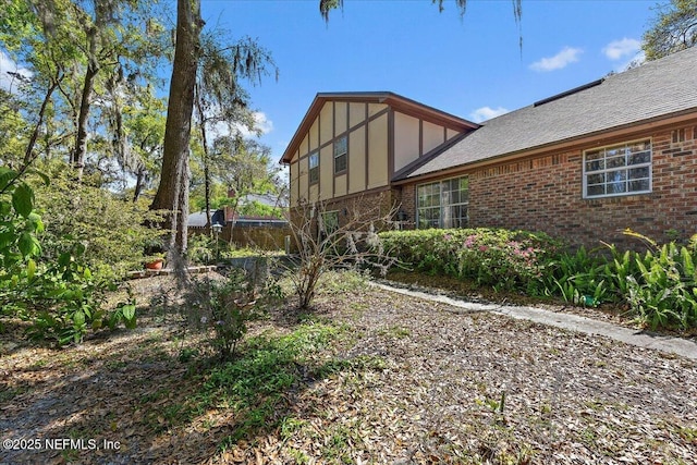 exterior space featuring brick siding and a shingled roof