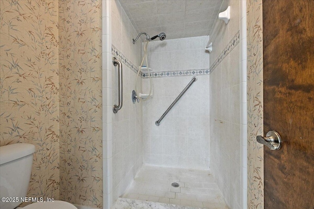 bathroom featuring wallpapered walls and tiled shower