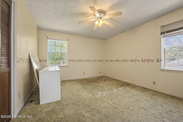 spare room with a ceiling fan, a textured ceiling, a healthy amount of sunlight, and carpet flooring