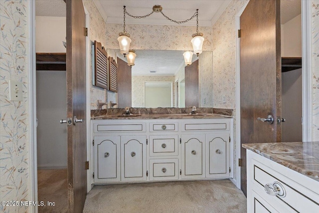 full bathroom featuring double vanity, a sink, and wallpapered walls