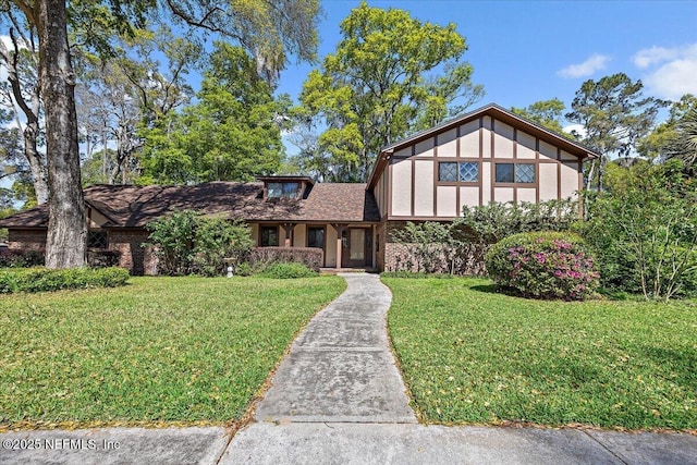 tudor home with a front lawn and brick siding