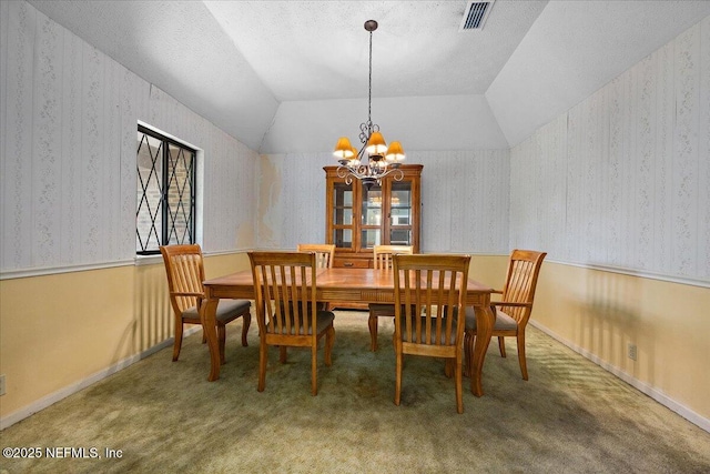 carpeted dining area featuring visible vents, an inviting chandelier, and wallpapered walls