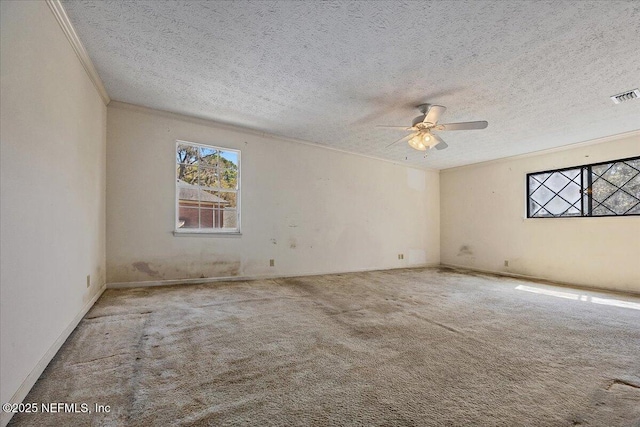 carpeted empty room with visible vents, a textured ceiling, crown molding, and a ceiling fan