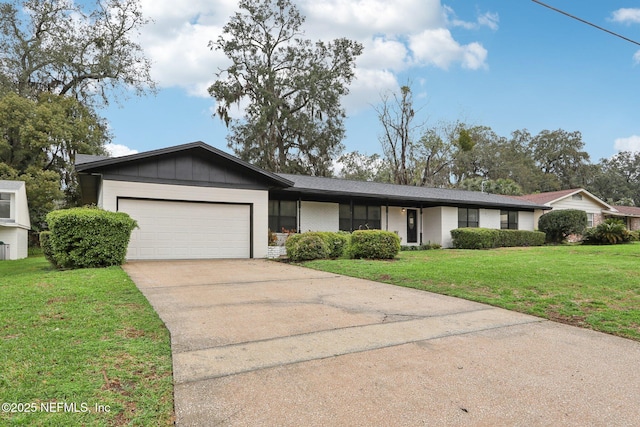 ranch-style house with board and batten siding, an attached garage, a front yard, and concrete driveway