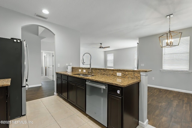 kitchen featuring visible vents, arched walkways, a sink, appliances with stainless steel finishes, and ceiling fan with notable chandelier