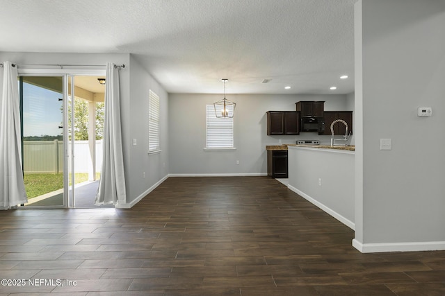 kitchen with baseboards, black microwave, dark wood finished floors, dark brown cabinetry, and a textured ceiling