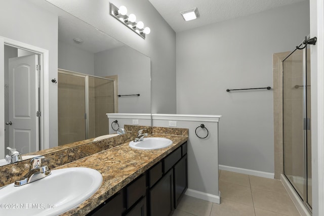 bathroom with a sink, baseboards, a stall shower, and tile patterned flooring