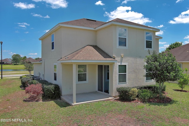 back of property featuring a shingled roof, a water view, a lawn, stucco siding, and a patio