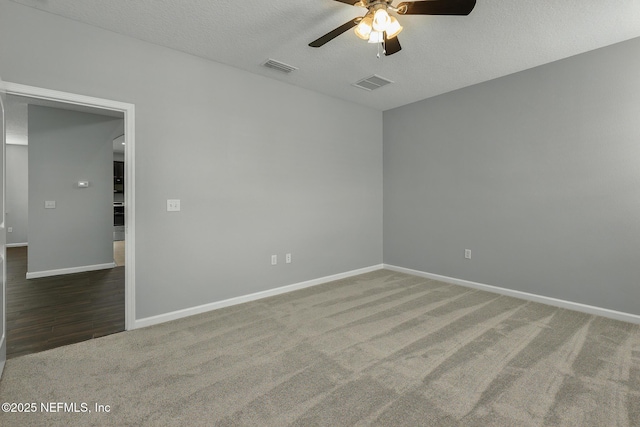 carpeted empty room featuring baseboards, visible vents, a textured ceiling, and a ceiling fan