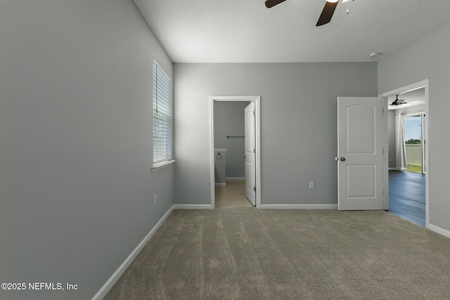 unfurnished bedroom with multiple windows, a textured ceiling, baseboards, and carpet floors