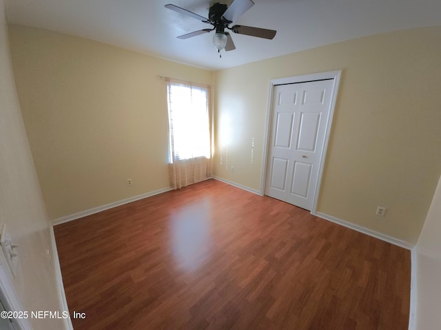 unfurnished bedroom with a closet, baseboards, wood finished floors, and a ceiling fan