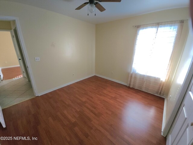 unfurnished room with plenty of natural light, ceiling fan, baseboards, and wood finished floors