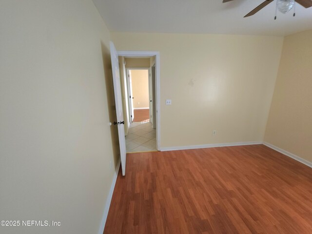 spare room featuring a ceiling fan, light wood-style floors, and baseboards