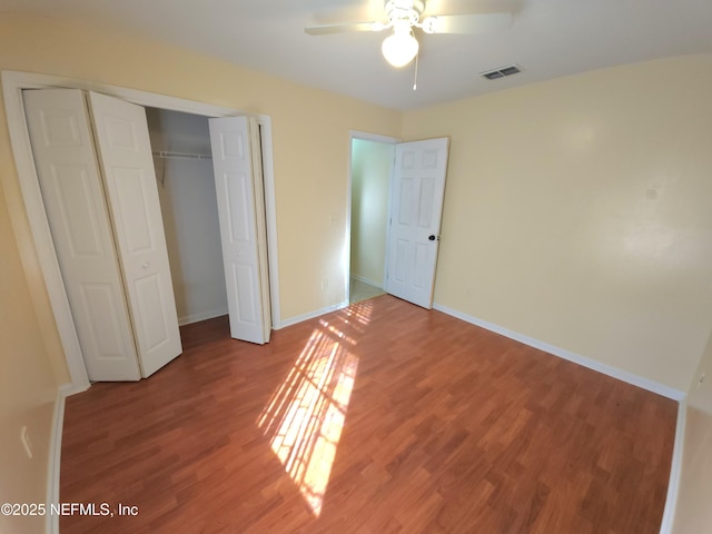 unfurnished bedroom with visible vents, ceiling fan, baseboards, wood finished floors, and a closet