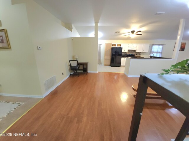 interior space with baseboards, visible vents, light wood finished floors, and a sink