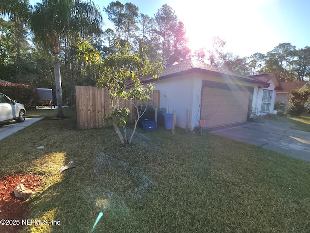 view of home's exterior with a yard, an attached garage, driveway, and fence