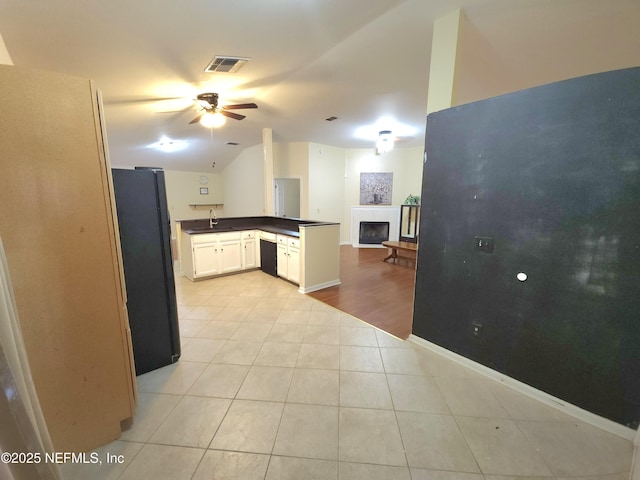 kitchen featuring visible vents, a sink, dark countertops, freestanding refrigerator, and dishwasher