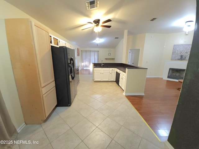 kitchen with a sink, visible vents, black appliances, and a fireplace